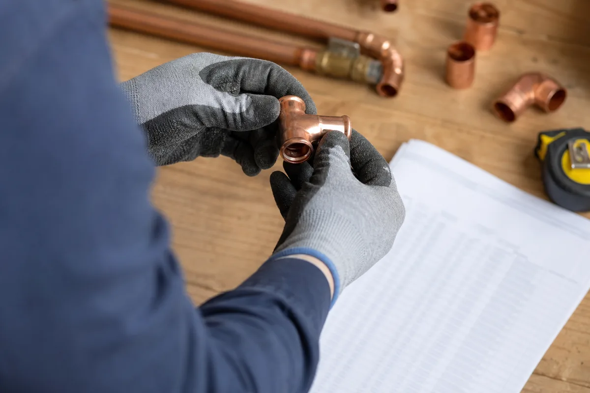 Artisan plombier vérifiant des raccords de tuyauterie en cuivre sur un plan de travail