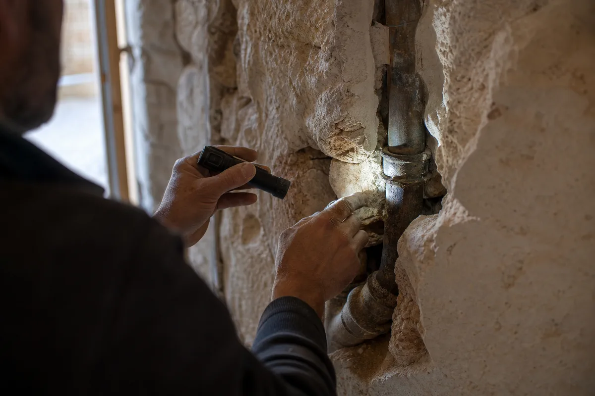 Mur en pierre épais d&rsquo;une maison ancienne du pays de Forcalquier avec tuyauterie apparente